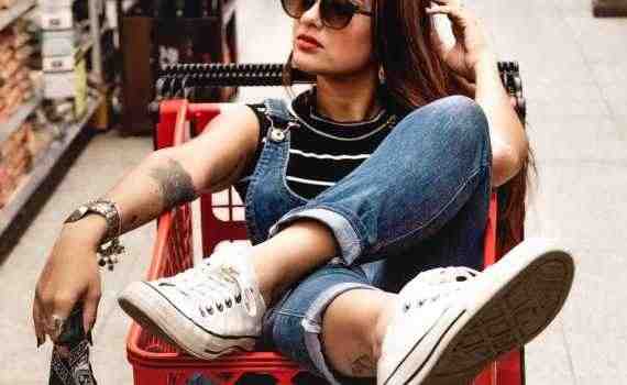 woman wearing blue jeans riding red shopping cart