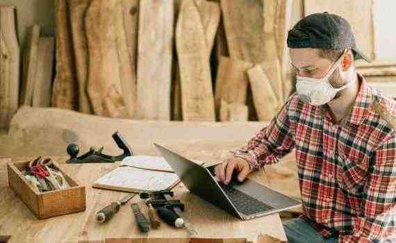 Man Using a Laptop at a Wood Workshop