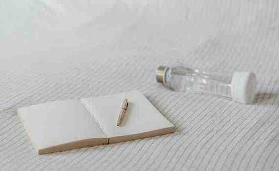 Empty notepad near decorative bottle on bed