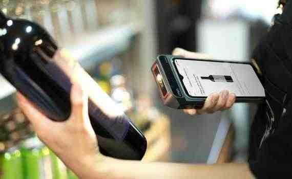Person Using Scanner on Bottle of Wine