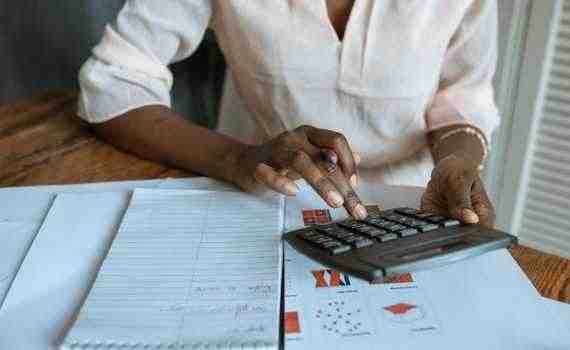 Person in White Dress Shirt Using A Calculator