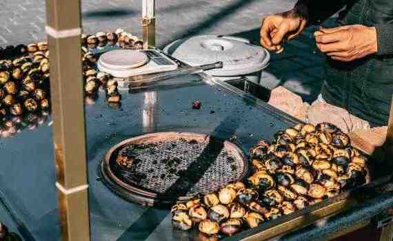 Crop man preparing delicious chestnuts on street