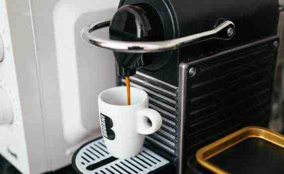 A coffee maker with a cup of coffee on it